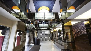 A modern hotel lobby with a central reception desk, glass railings, and a patterned wall. - Baiyoke Boutique (Bangkok)
