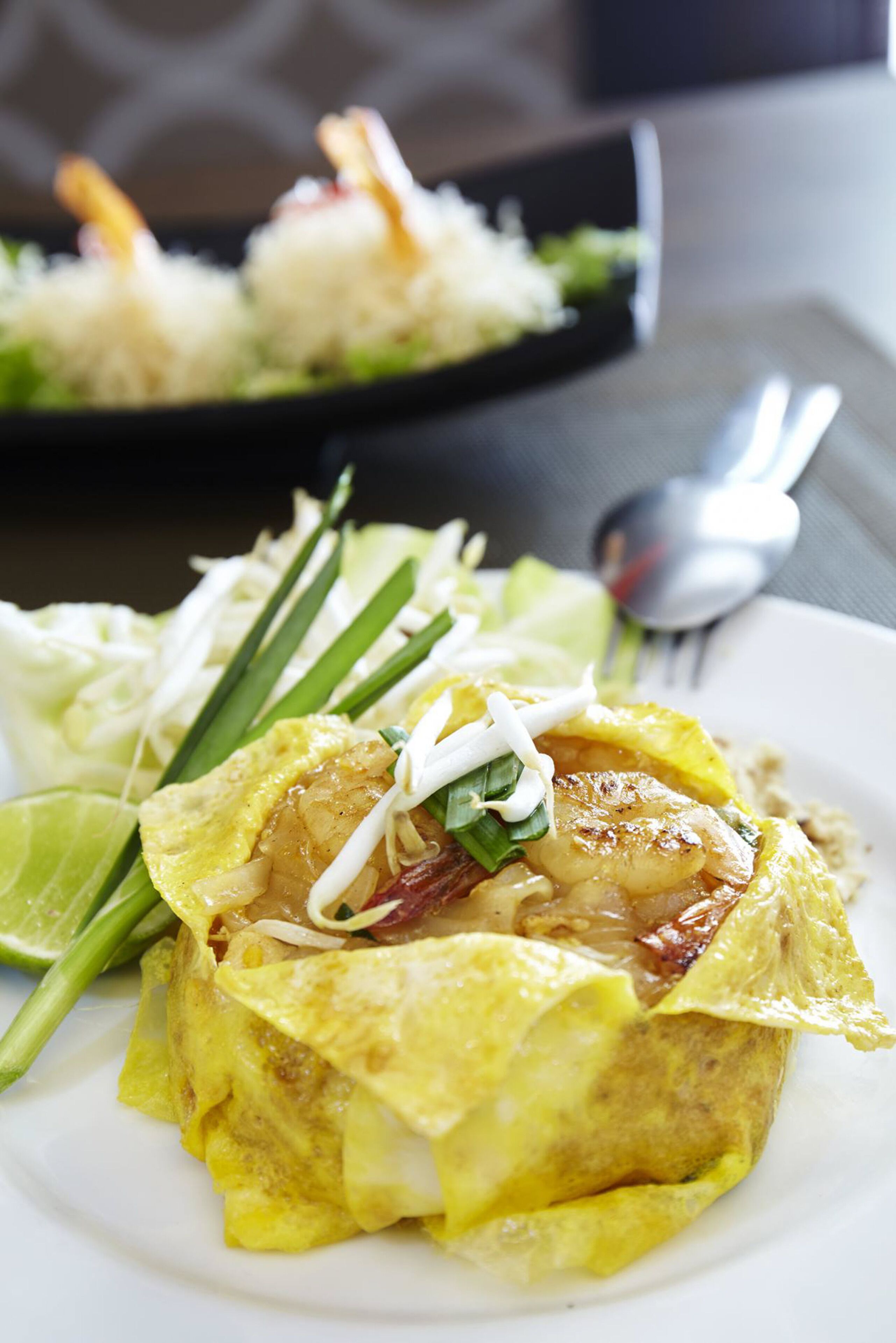 A plate of food with a yellow omelette, shrimp, and vegetables.