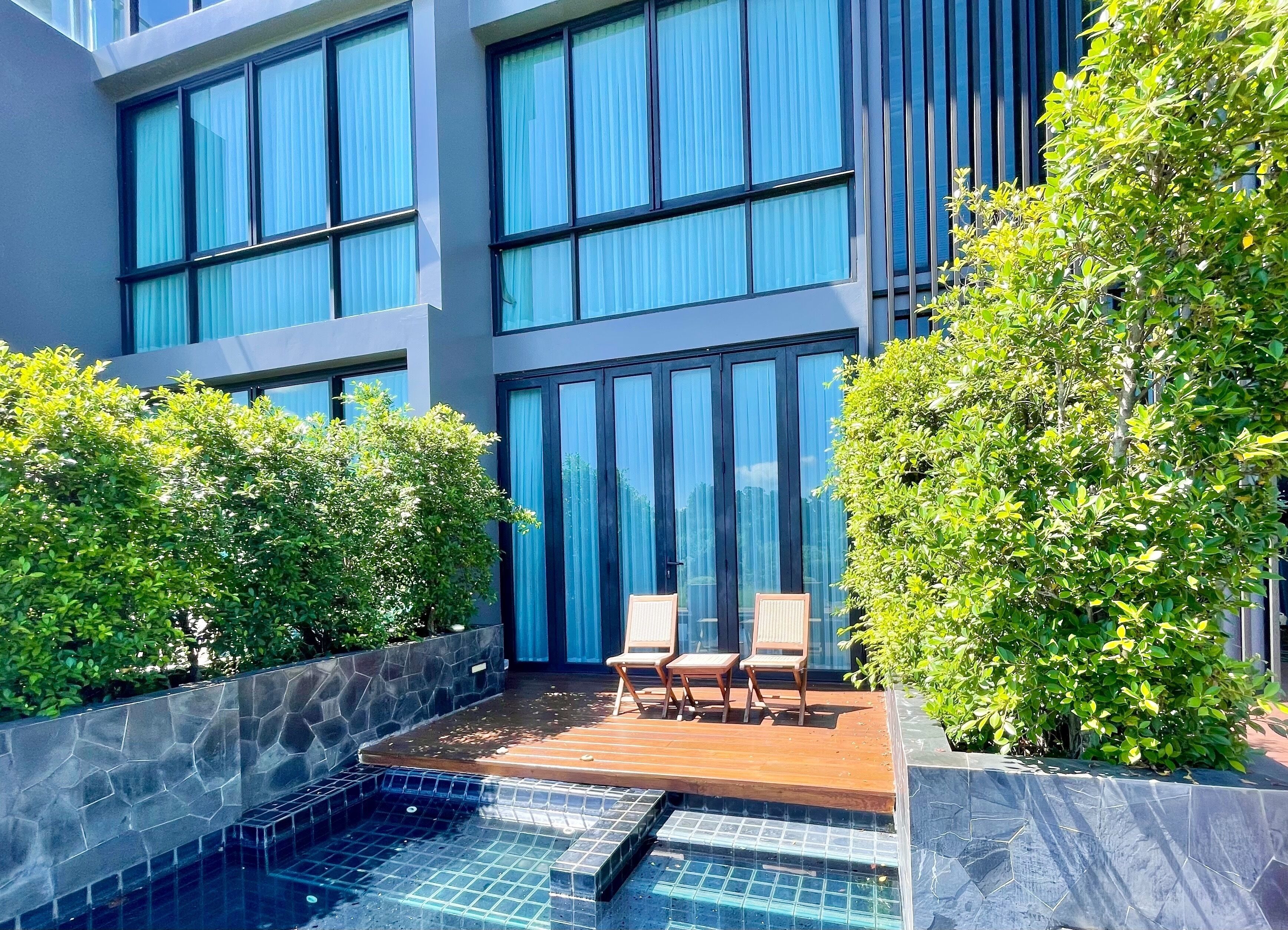 A modern building with large windows, a swimming pool, and outdoor seating.