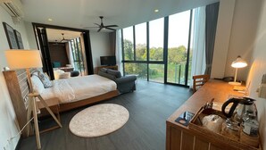 Ein modernes Hotelzimmer mit einem großen Bett, einem Schreibtisch, einem Sessel, einem Fernseher und einem Balkon mit Blick ins Freie.