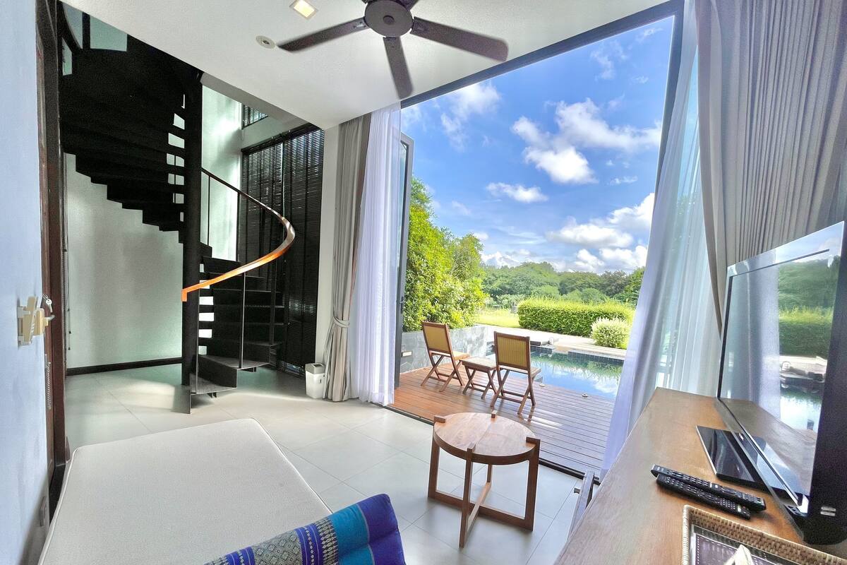 Quarto moderno com escadaria em espiral, piscina e vista para o verde.
