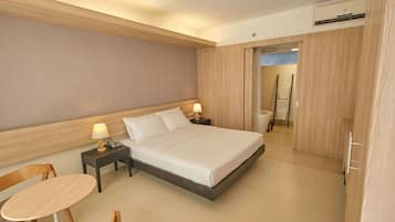 A hotel room with a bed, bedside tables, a chair, and a small table.