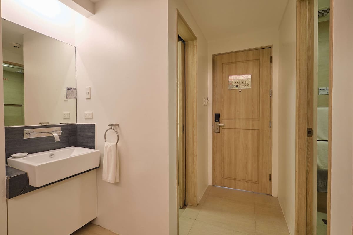 A bathroom with a large mirror, a sink, and a towel rack.