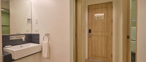 A bathroom with a large mirror, a sink, and a towel rack.