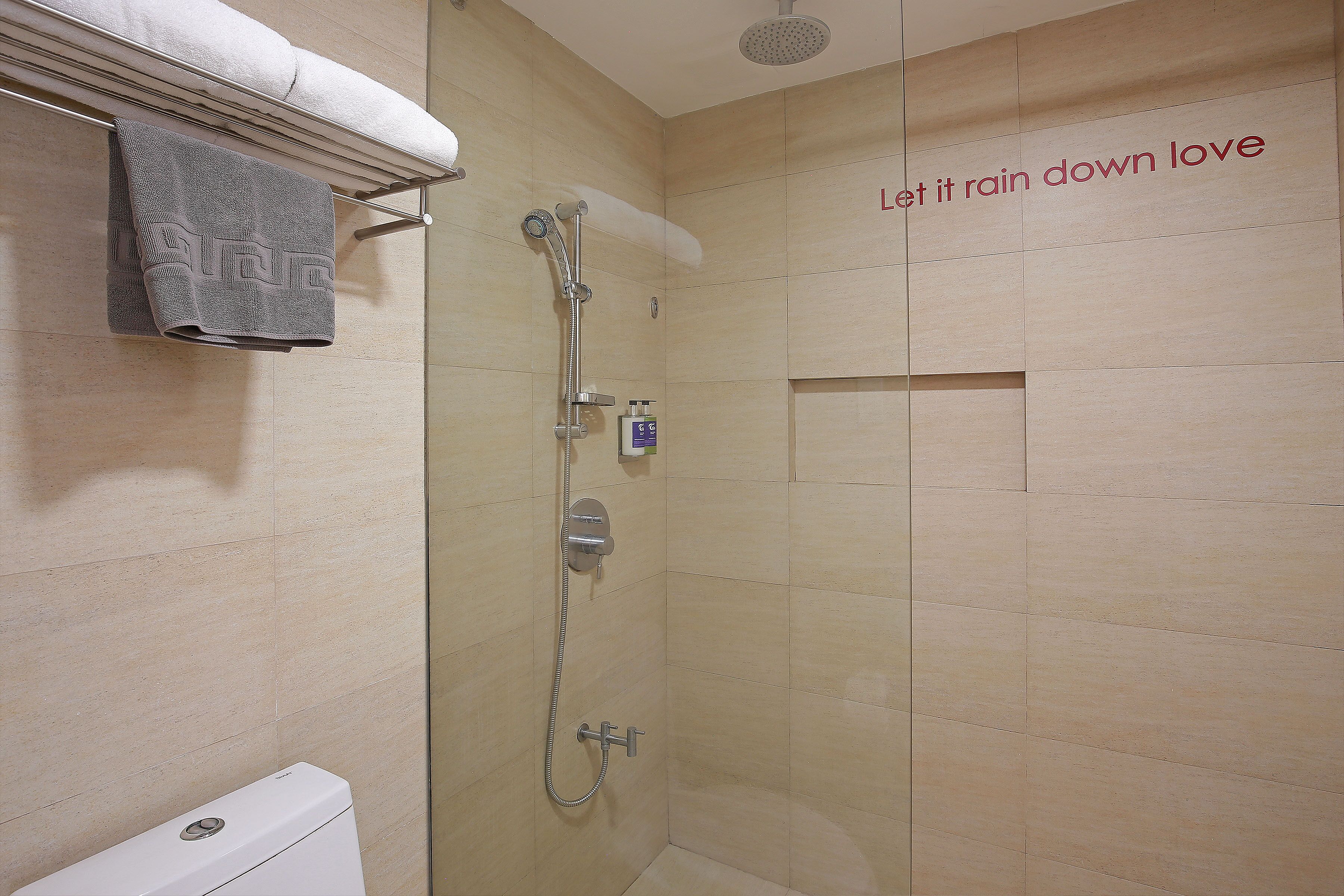 A shower area with a towel rack, a handheld showerhead, and a wall-mounted control panel.