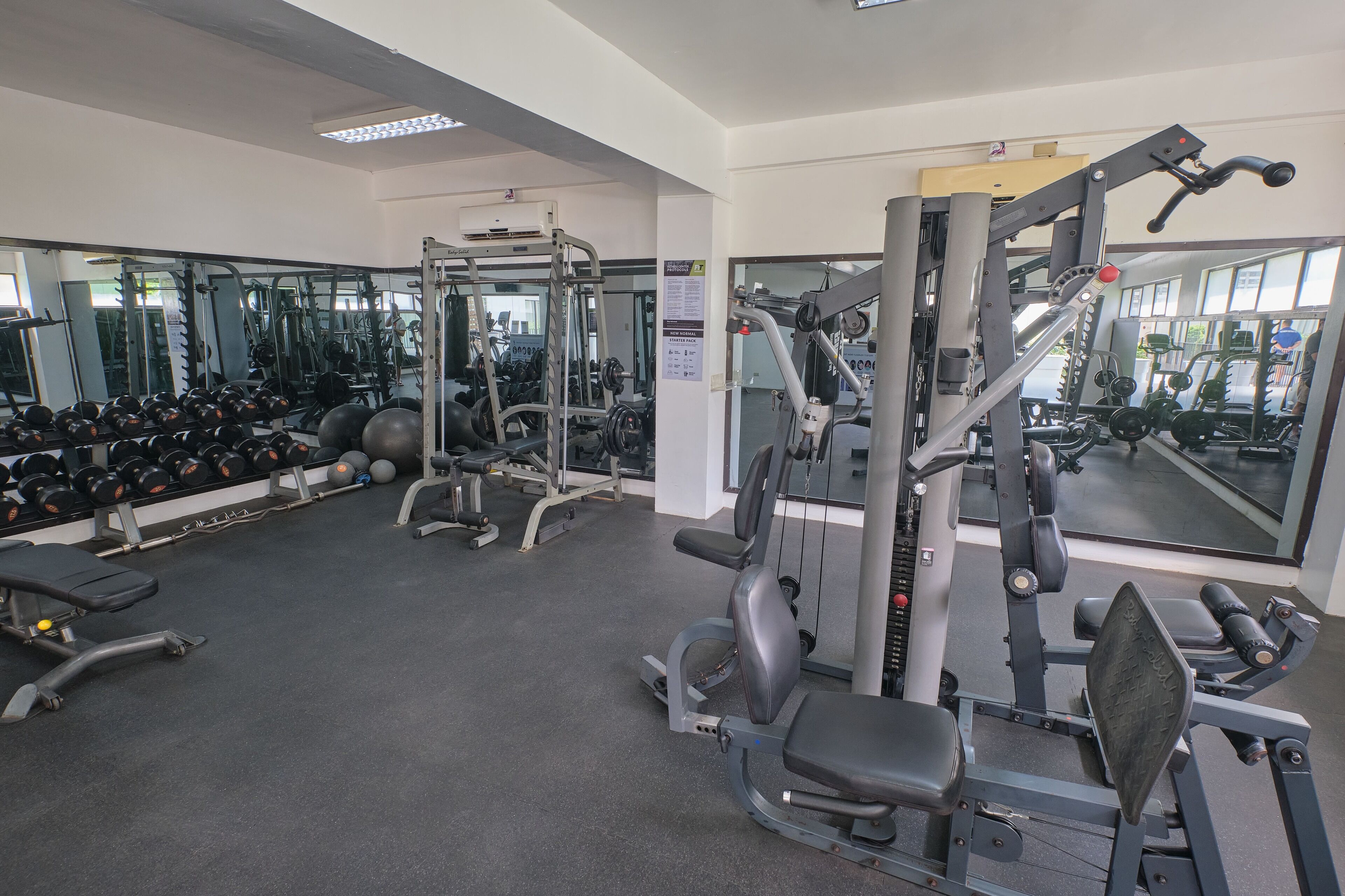 A gym with various exercise equipment, mirrors, and weights.