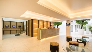 Un área de recepción moderna con mostrador, zona de estar y escalera.