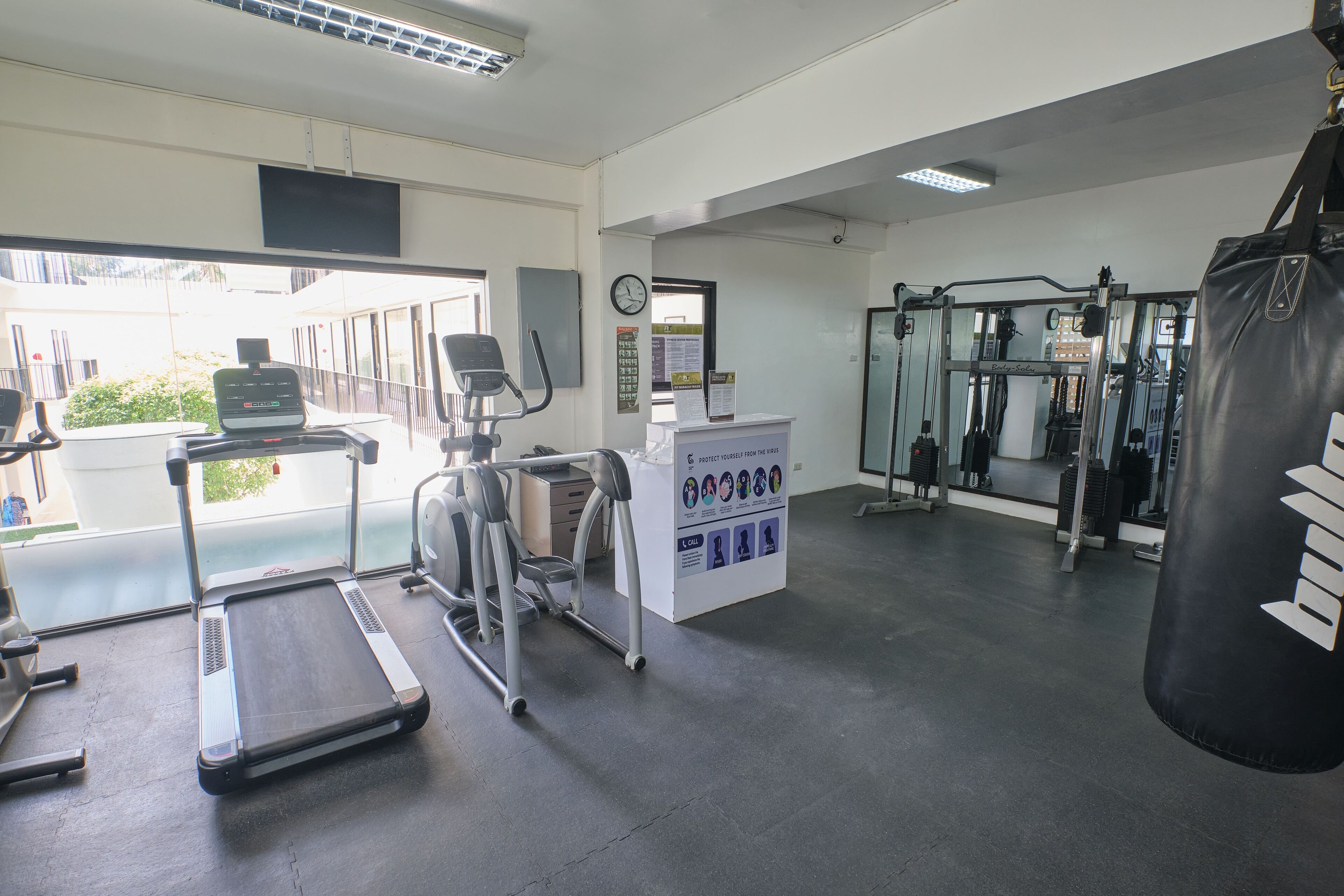 Un gimnasio con cintas de correr, una bicicleta estática, un saco de boxeo y una máquina de pesas.