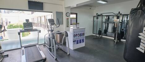 Un gimnasio con cintas de correr, una bicicleta estática, un saco de boxeo y una máquina de pesas.
