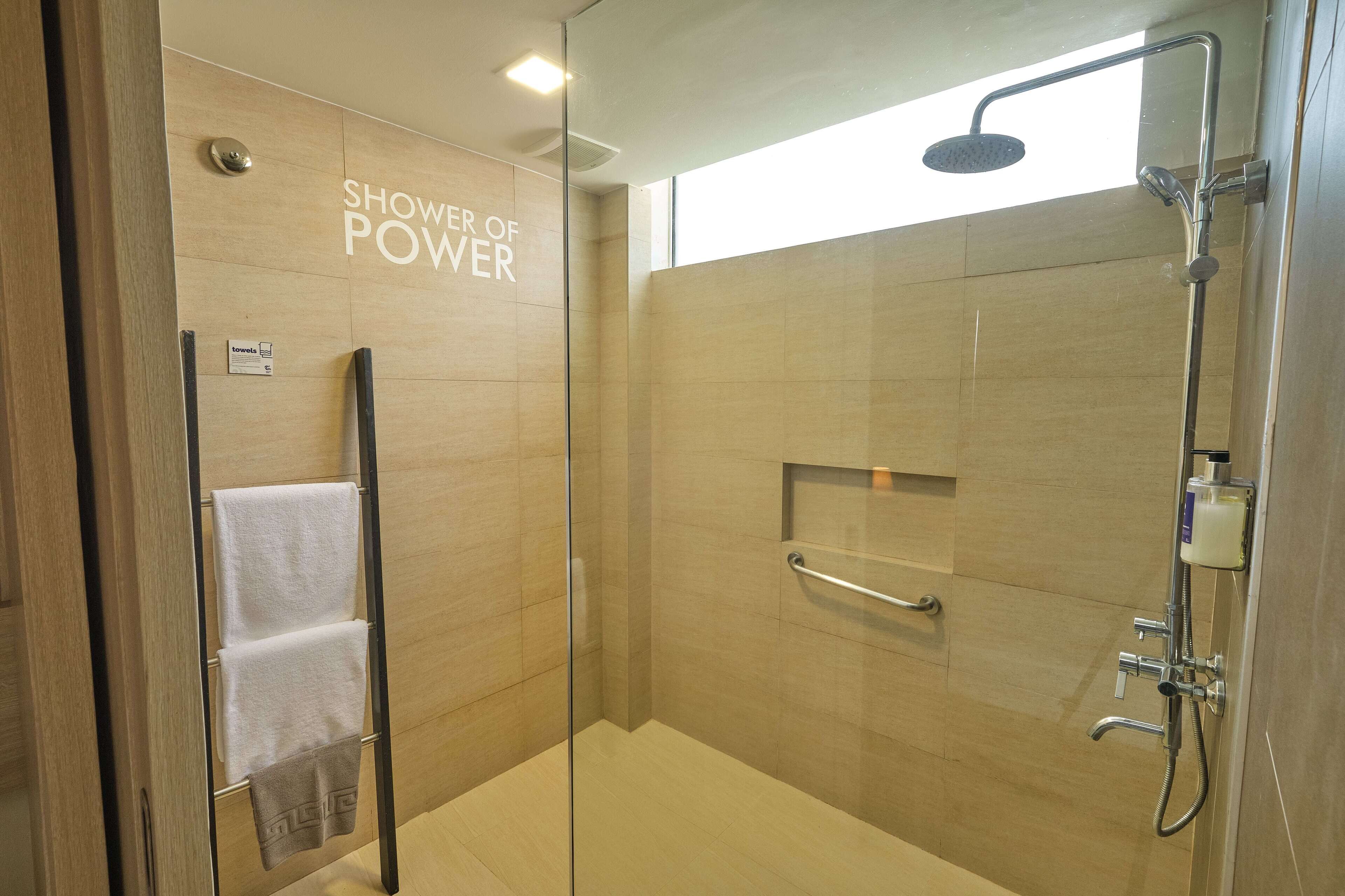 A modern shower with a glass door, a towel rack, and a sign that reads "Shower of Power".