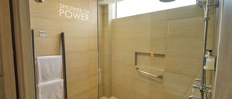 Una ducha moderna con puerta de vidrio, un perchero y un letrero que dice "Shower of Power".