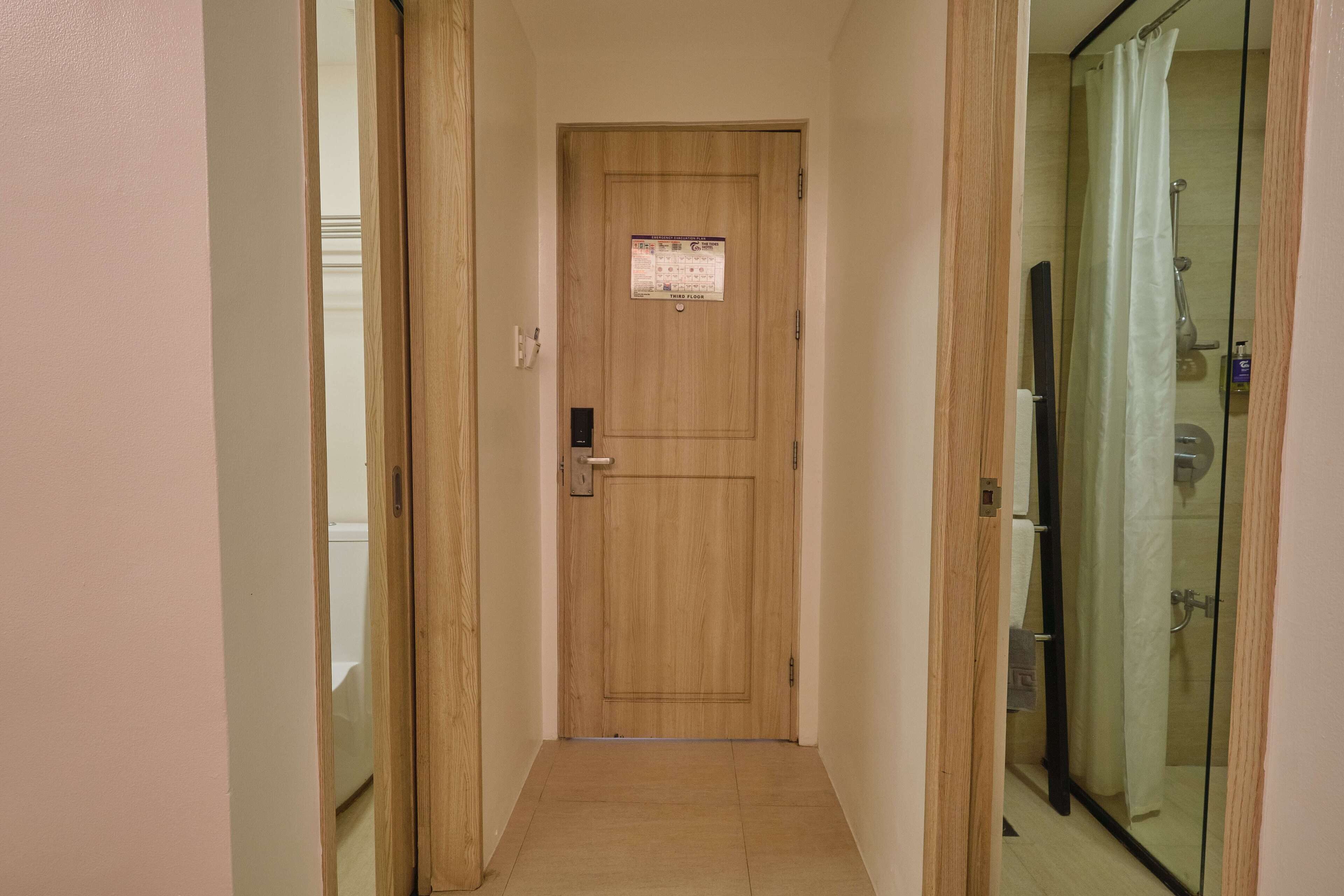 Un pasillo estrecho con una puerta de madera y una zona de ducha de vidrio.