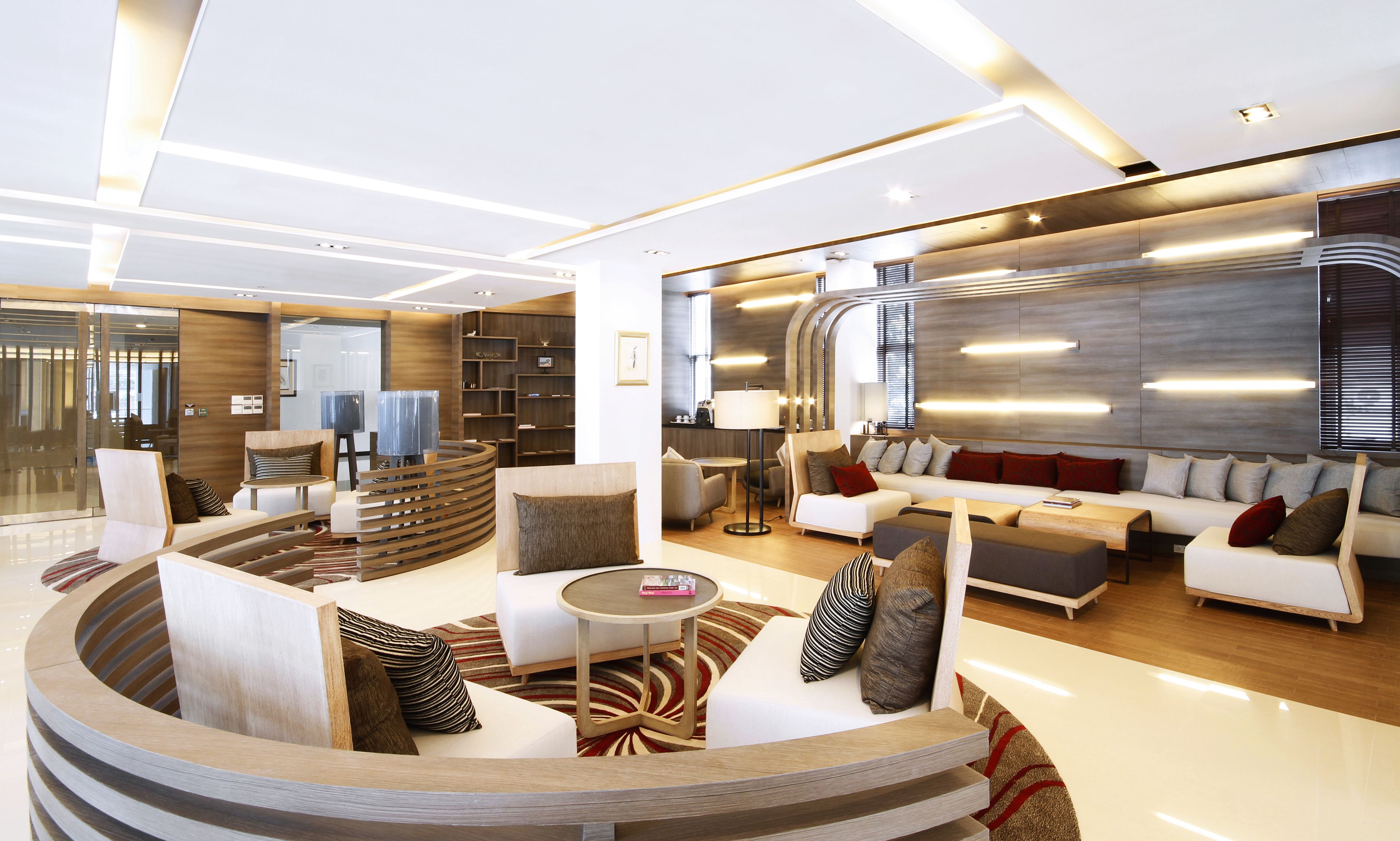 A modern, well-lit living area with a curved seating arrangement, a coffee table, and a sofa set.