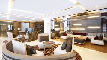 A modern, well-lit living area with a curved seating arrangement, a coffee table, and a sofa set.