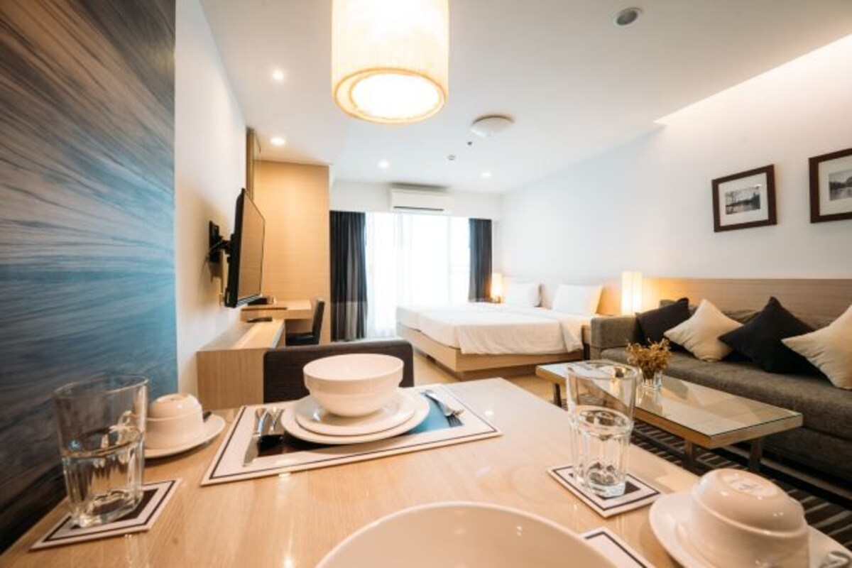 Una habitación de hotel moderna con comedor, cama, sofá y televisión.