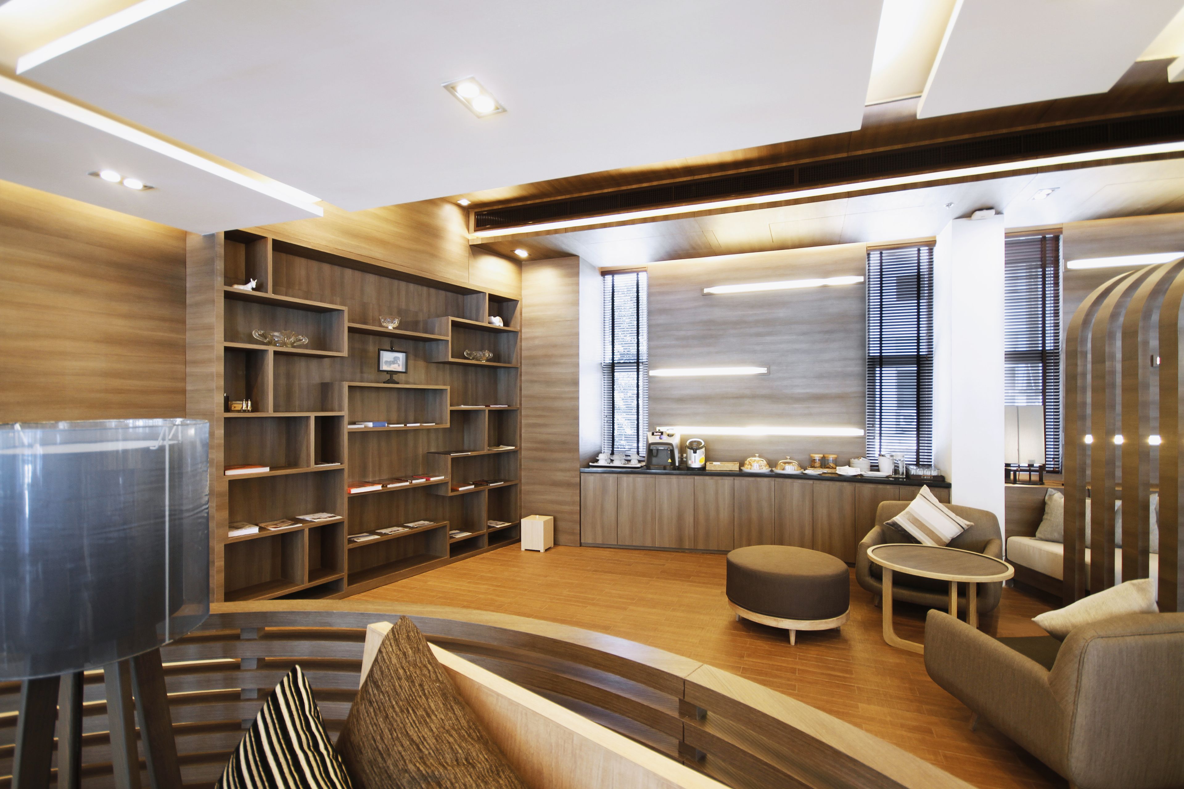 A modern interior with a wooden floor, a seating area with a round table, and a kitchen area with a counter and appliances.