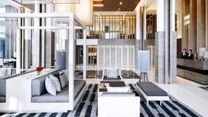 Eine moderne Hotellobby mit Empfangstresen, Sitzgelegenheiten und einer Treppe zu einer oberen Ebene.