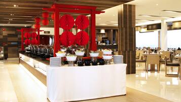A buffet setup with various food stations, a red decorative structure, and a clean, modern interior.