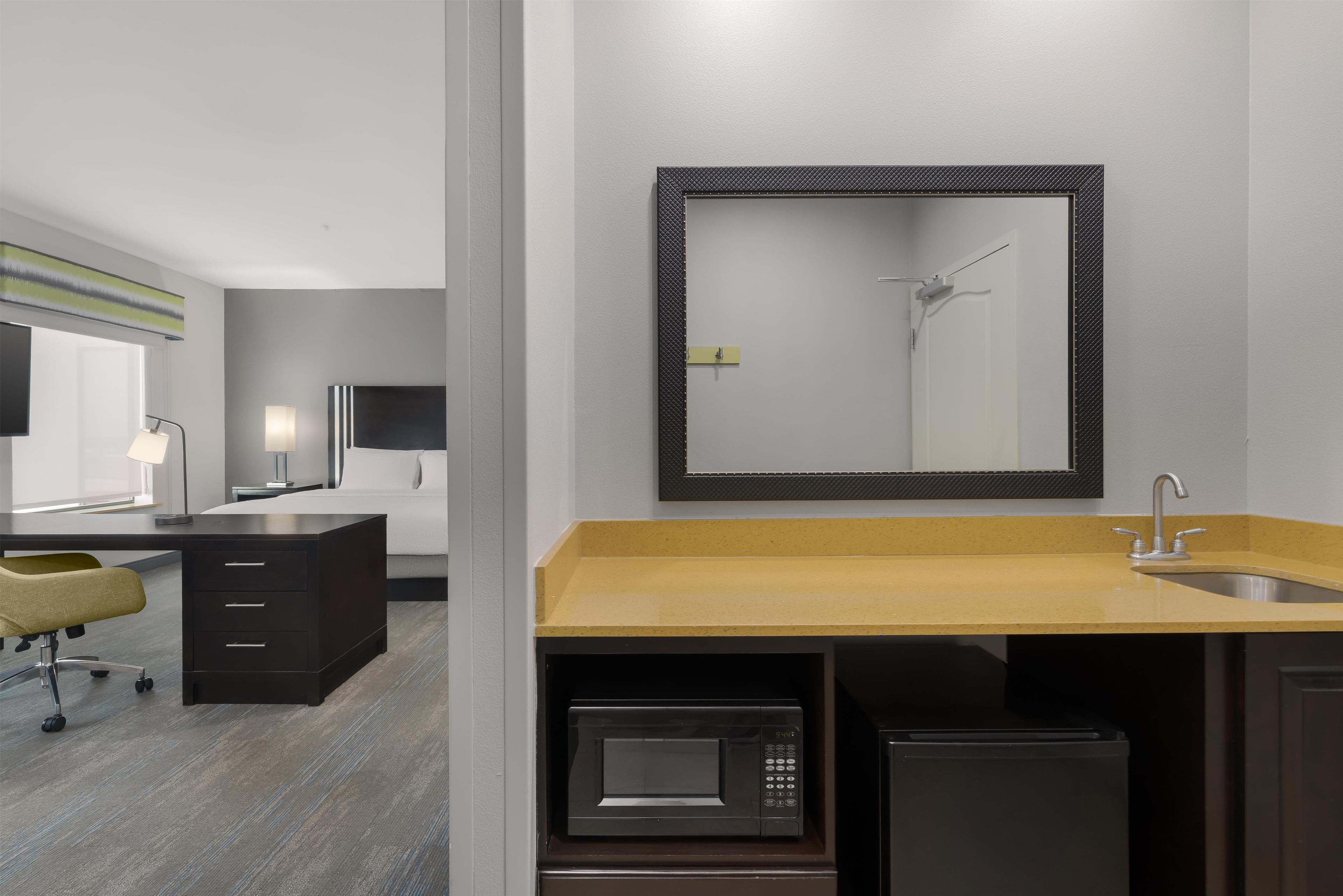 A modern bathroom with a sink, mirror, and microwave.