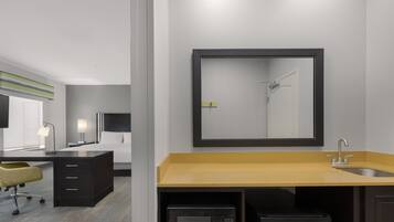 A modern bathroom with a sink, mirror, and microwave.