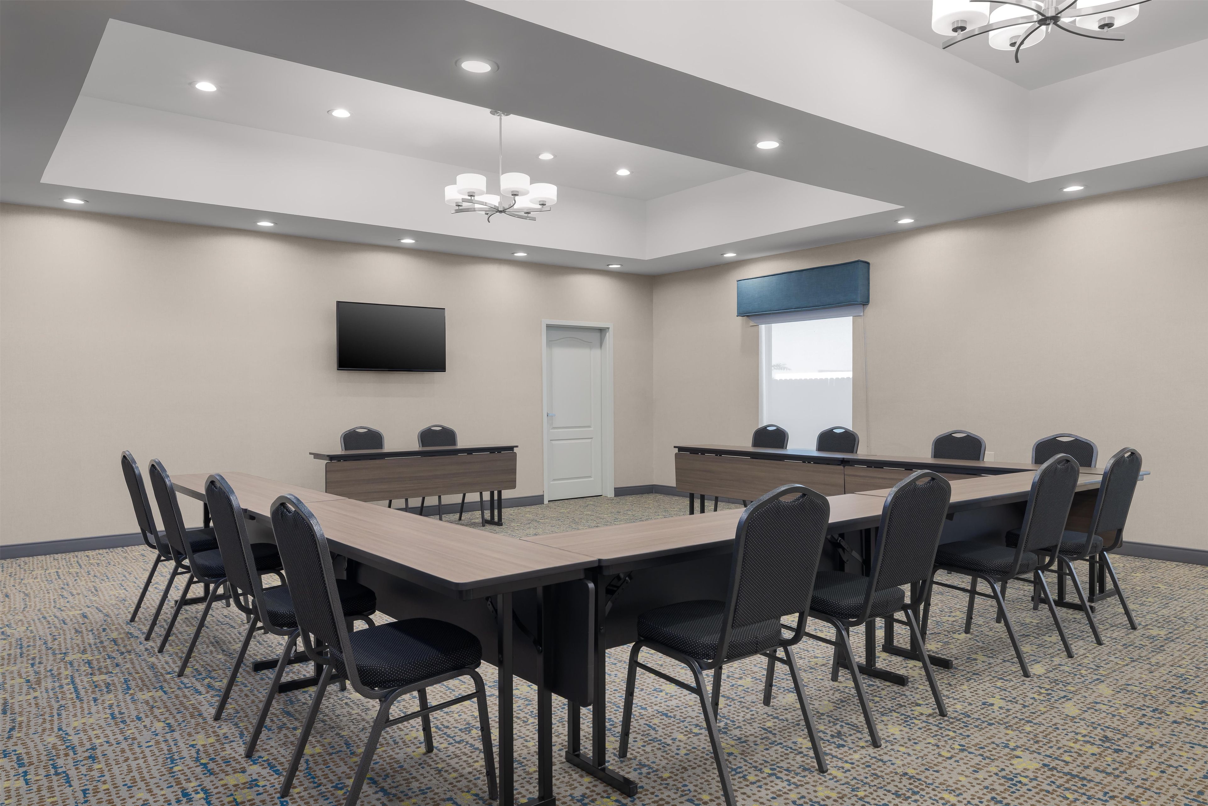 Une salle de conférence équipée d’une longue table, de chaises, d’un téléviseur à écran plat et d’un luminaire au plafond.