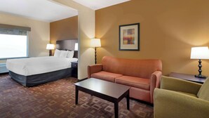 Une chambre d’hôtel avec un lit, un canapé, une table basse et deux lampes.