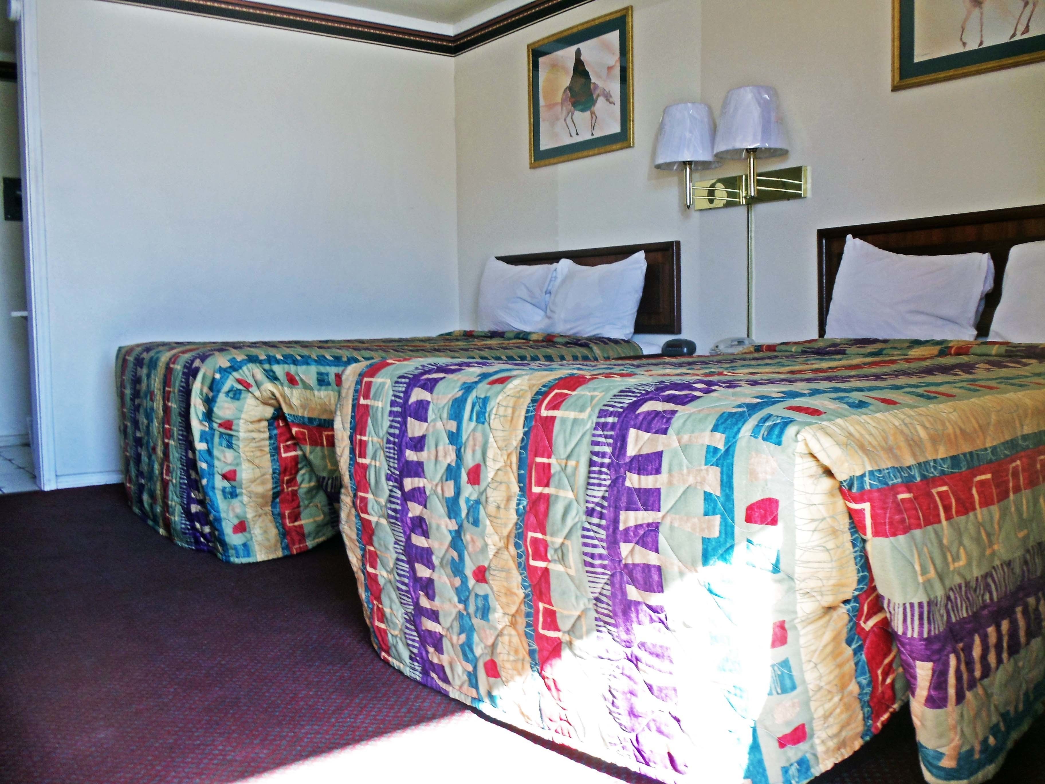 Una camera d'albergo con due letti singoli, una grande finestra e un quadro appeso al muro.