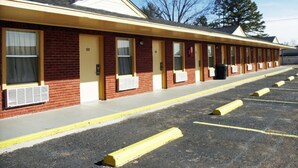 A motel with a row of rooms, each with a door and window, and a parking lot in front. - Antlers Budget Inn (Antlers)