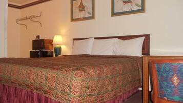 Habitación de hotel con una cama grande, una mesita de noche con lámpara y dos cuadros en la pared.
