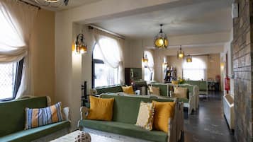 A hotel lobby with green sofas, yellow cushions, and decorative lighting fixtures.