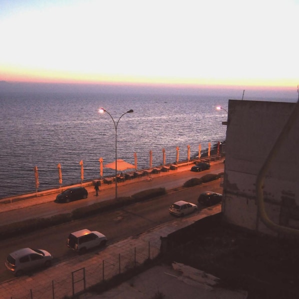 A coastal road with street lamps, parked cars, and a view of the sea at dusk. - Hotel Alkyon (Alexandroupoli)