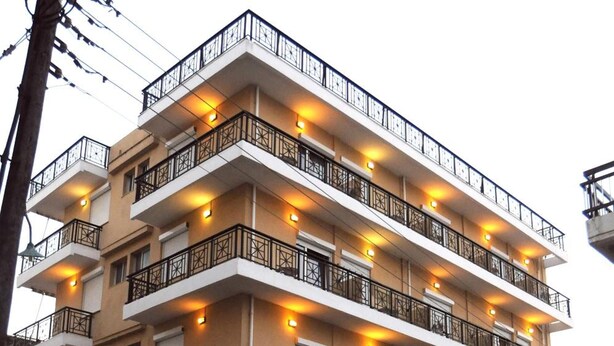 A multi-story hotel with balconies, a ground-level entrance, and a flag.
