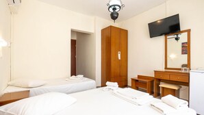 A hotel room with two beds, a wooden wardrobe, a desk with a chair, a television mounted on the wall, and a ceiling light fixture. - Hotel Alkyon (Alexandroupoli)