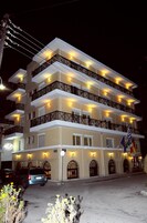 Un hotel de varios pisos con balcones, un estacionamiento y banderas.