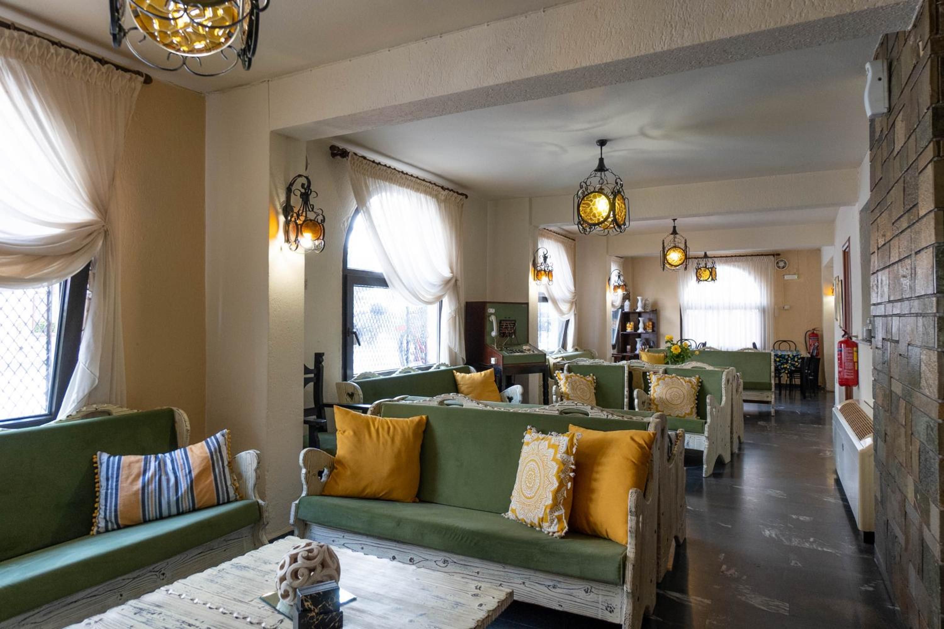 Un hall de hotel con sofás verdes, cojines amarillos e iluminación decorativa.