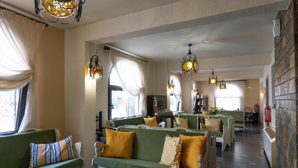 A hotel lobby with green sofas, yellow cushions, and decorative lighting fixtures. - Hotel Alkyon (Alexandroupoli)