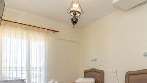 Habitación de hotel con dos camas, un escritorio, una silla, una lámpara y un ventanal con cortinas.