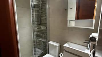 A modern bathroom with a glass shower enclosure, a toilet, a sink, and a mirror.