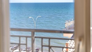 A view of the sea from a balcony with a railing, a street lamp, and a building with a balcony. - Hotel Alkyon (Alexandroupoli)