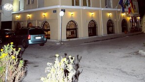 A multi-story hotel with balconies, a parking area, and flags. - Hotel Alkyon (Alexandroupoli)