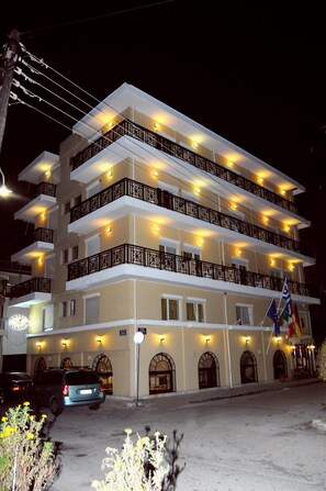 A multi-story hotel with balconies, a parking area, and flags. - Hotel Alkyon (Alexandroupoli)