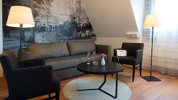 A modern living room with a sofa, two armchairs, a round coffee table, and two floor lamps.