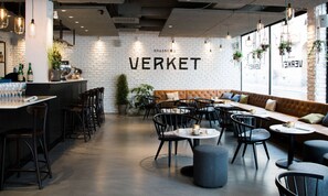 A modern cafe interior with a brick wall, wooden bar, and seating area. - Scandic Sundsvall City (Sundsvall)
