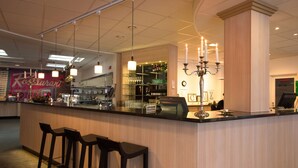 A bar area with a counter, stools, a chandelier, and a bar stocked with glasses and bottles. - Scandic Sundsvall City (Sundsvall)