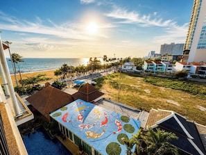 A rooftop pool with koi fish mural, a view of the beach, and surrounding buildings. - Royal Thai Pavilion Jomtien Boutique Resort (Pattaya)