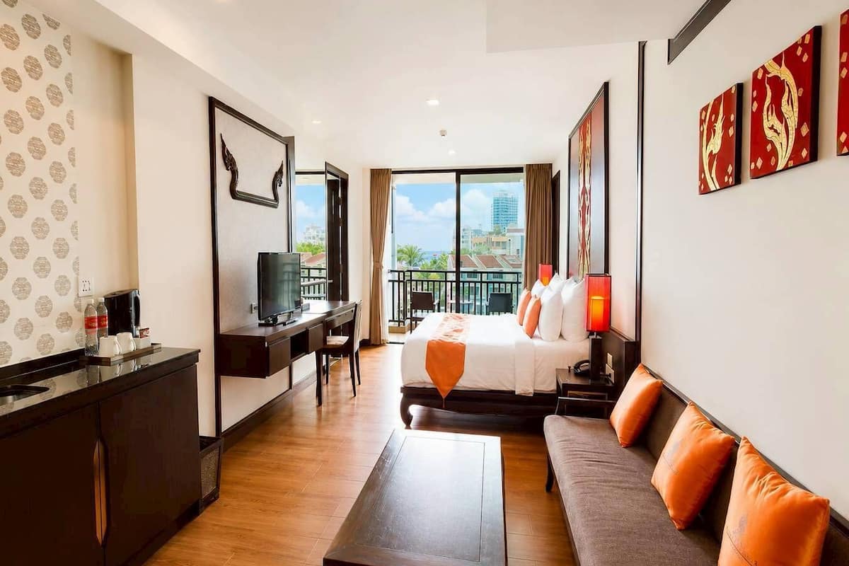 Une chambre d’hôtel équipée d’un lit, d’un canapé, d’un bureau, d’une télévision et d’un balcon avec vue sur la ville.