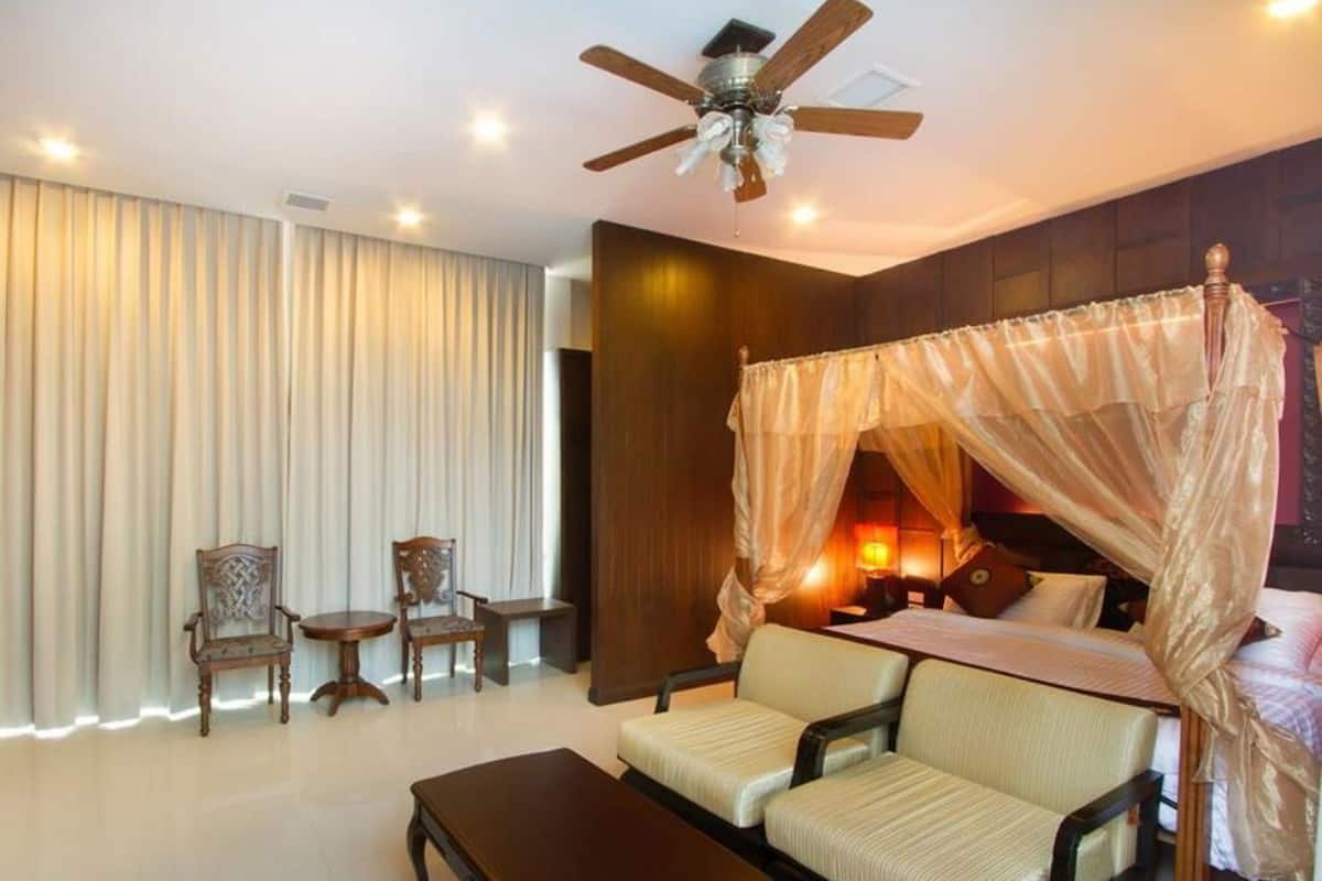 Une chambre à coucher avec un lit à baldaquin, un ventilateur de plafond, un bureau et deux chaises.