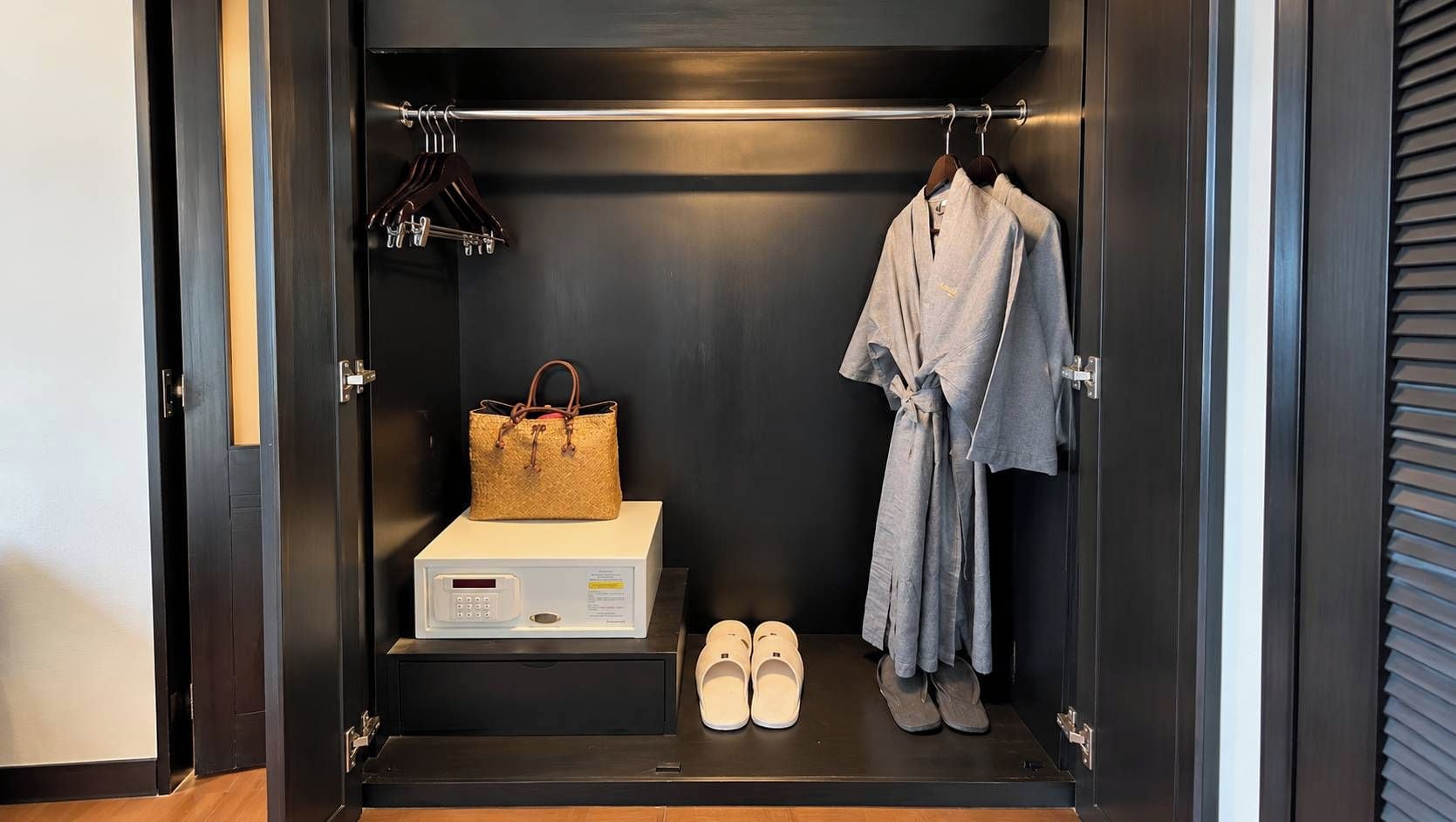 Armadio a muro con appendiabiti, una valigia, una borsa, un forno a microonde e un paio di scarpe.