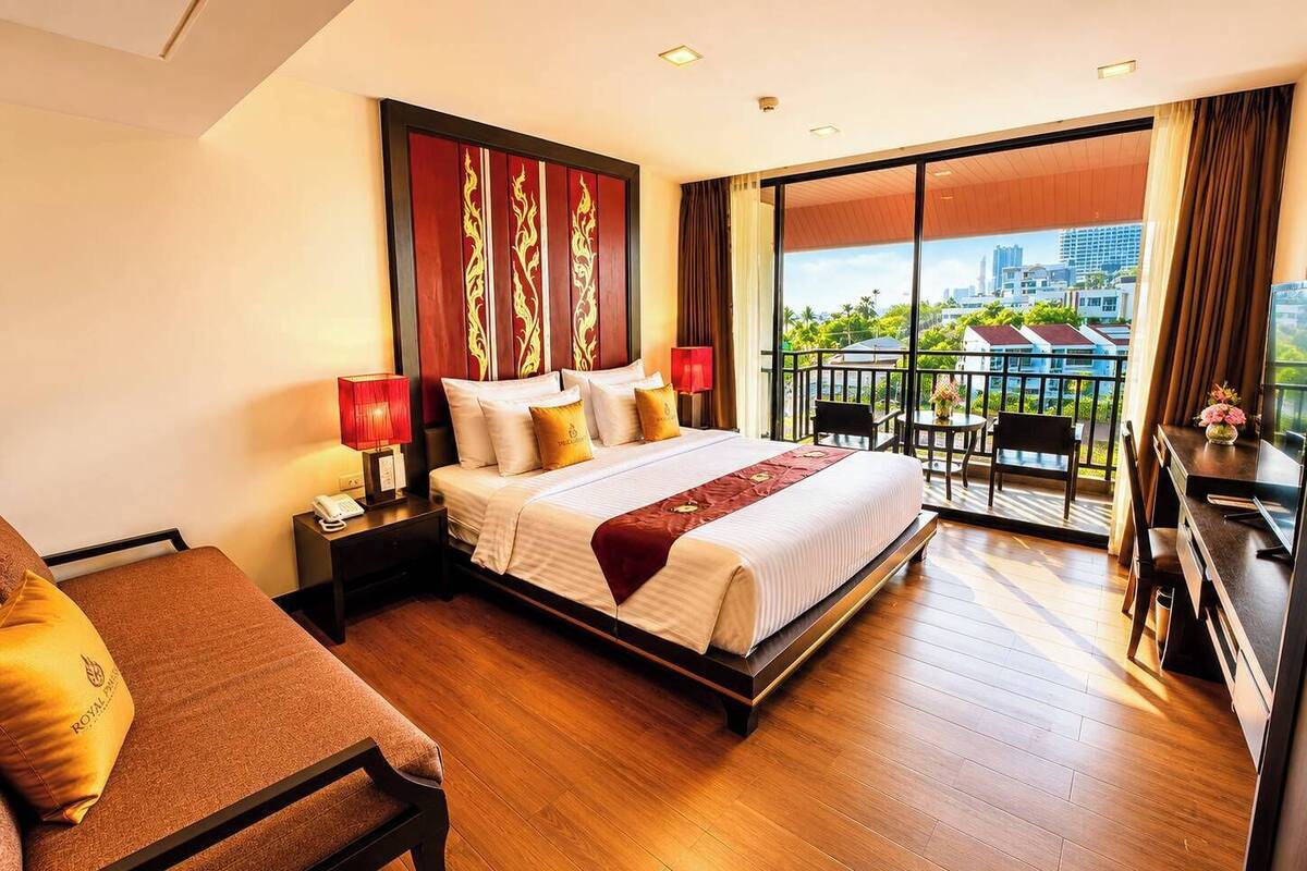 Une chambre d’hôtel avec un grand lit, un bureau, une chaise et un balcon offrant une vue sur la ville.