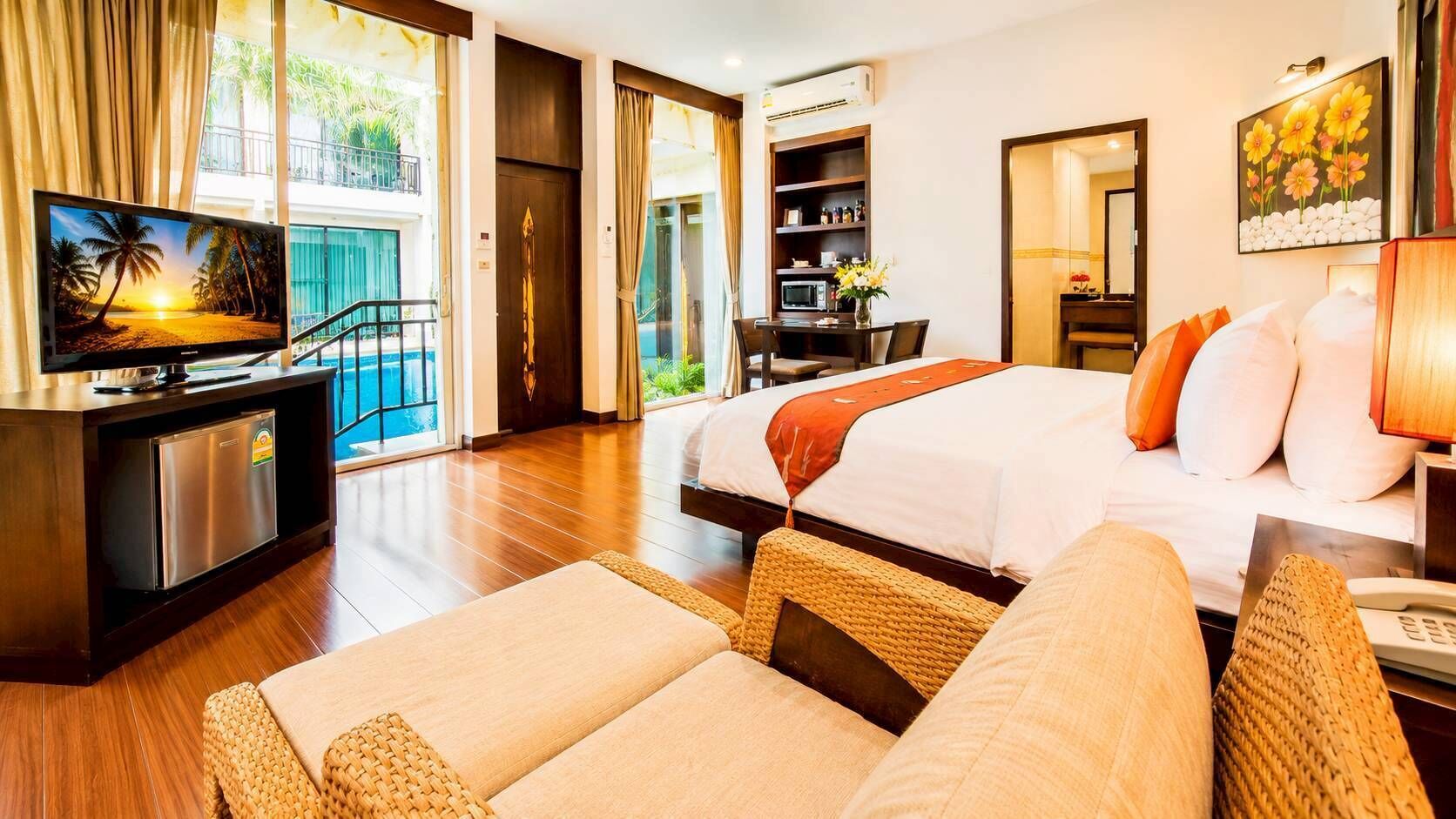 A hotel room with a bed, a desk with a computer, a TV, and a view of the outdoors.
